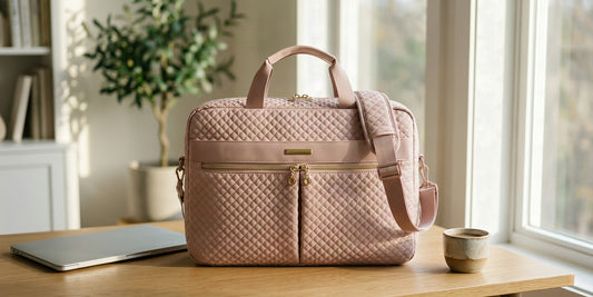 Sac ordinateur femme rose matelassé posé sur un bureau lumineux à côté d'un ordinateur portable